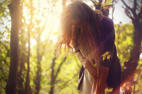 Long-haired girl in the sunlight against the background of trees