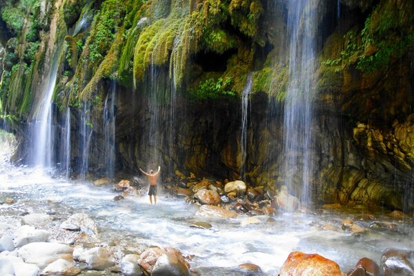 Homme debout sous une cascade en Grèce