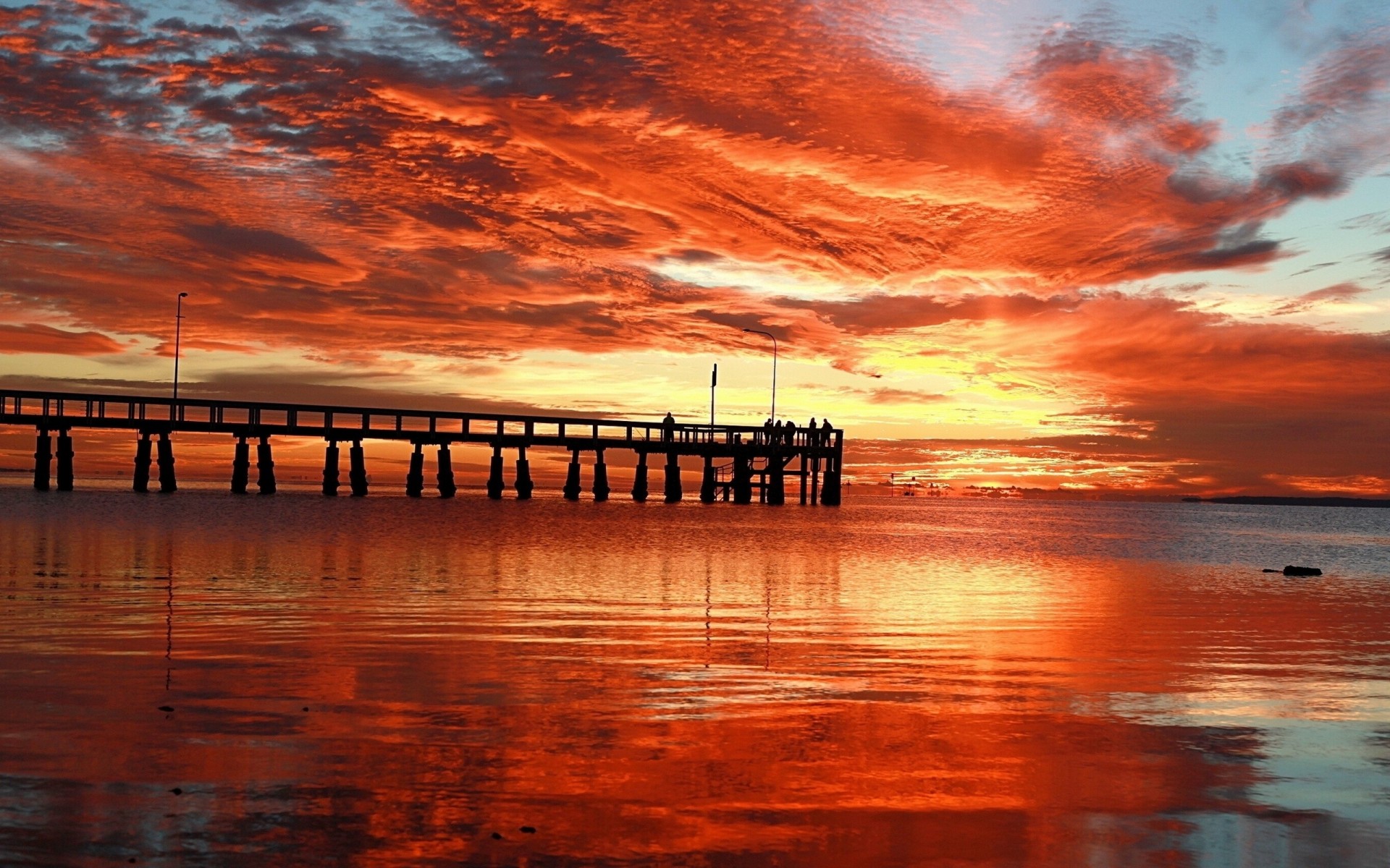 tramonto molo cielo notte nuvole mare arancione ponte struttura persone