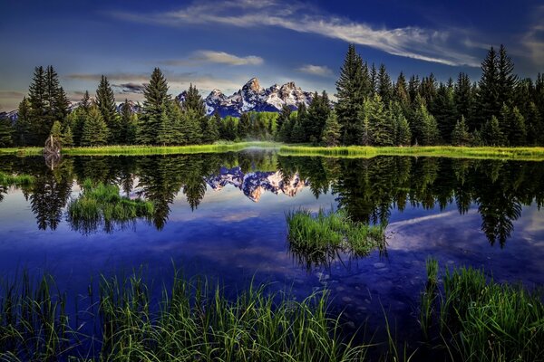 Die felsigen Berge und die Waldlandschaft spiegelt die Tiefe des blauen Wassers des Sees wider