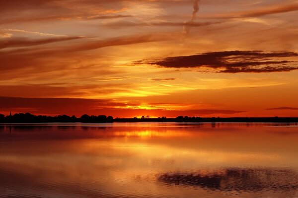 Zachód słońca na spokojnym jeziorze na tle nieba