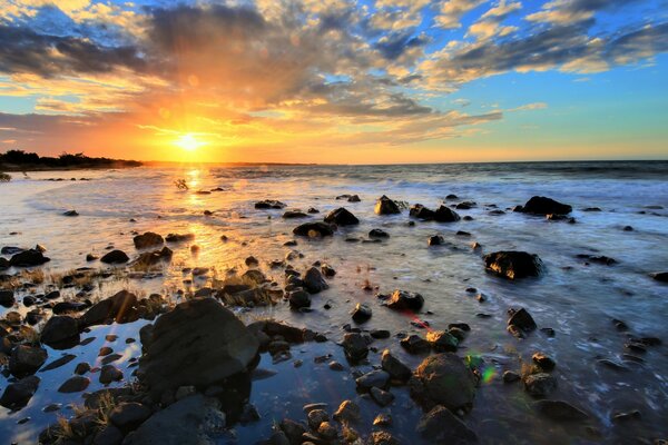 Mar con piedras en el fondo de la puesta de sol