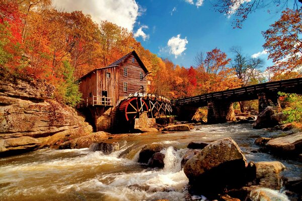 Herbstfoto einer Mühle, die am Fluss steht