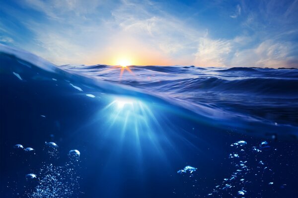 Bubbles under the water and sunset rays on the ocean
