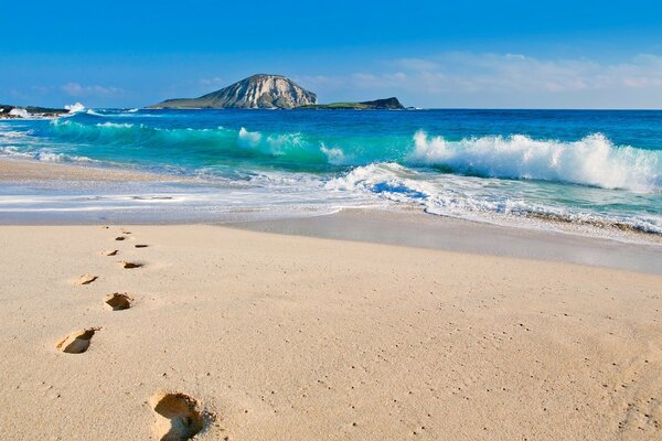 Spuren im Sand am Meer mit Wellen