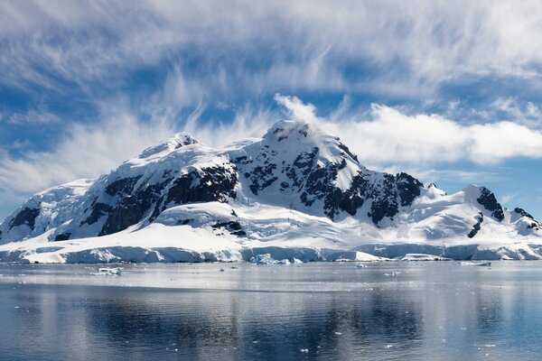 Montañas cubiertas de nieve en las nubes y un lago en el hielo