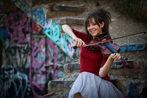 Lindsey Stirling spielt Geige vor dem Hintergrund einer Graffiti-gezeichneten Treppe