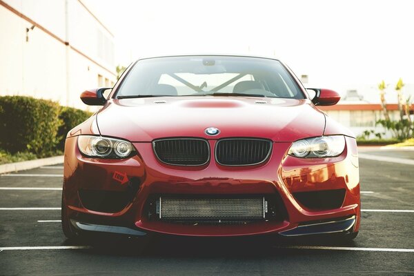 BMW rouge à côté du bâtiment sur le parking