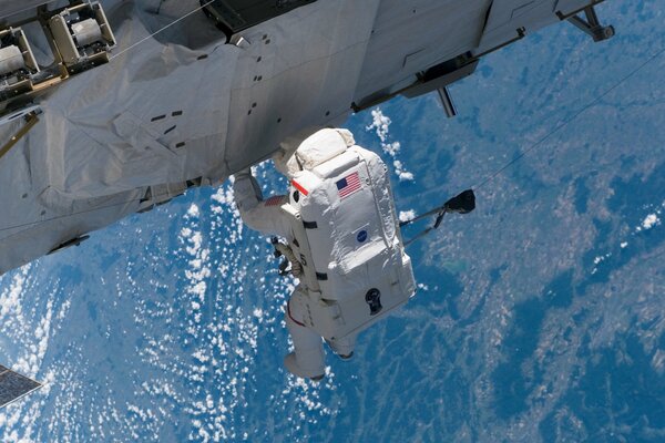 An astronaut outside the ISS on the background of the Earth s surface
