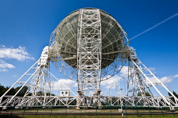 Un enorme radiotelescopio de placa contra un cielo azul nublado