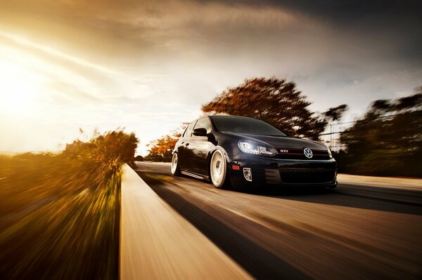 A black Volkswagen is speeding along the highway