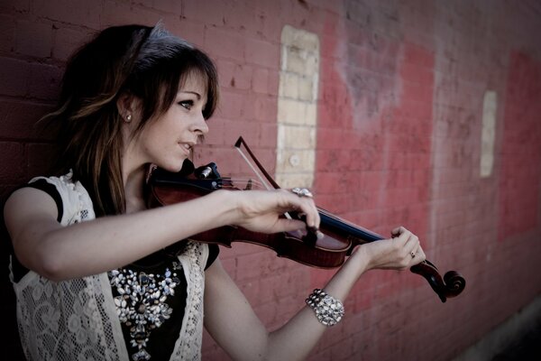 Lindsay Stirling contra una pared de ladrillo