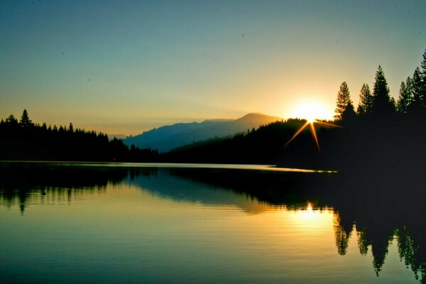 Sonnenuntergang über bewaldeten Bergen und Seen