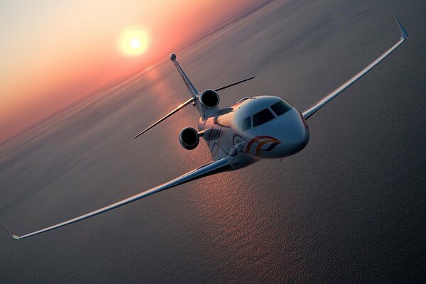 The plane is flying over the sea. Beautiful sunset