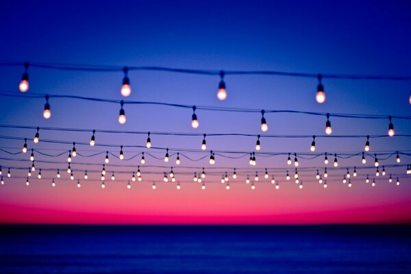 Burning lamps on wires on the background of sunset