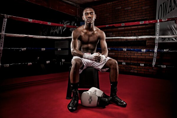 Dunkelhäutiger Boxer sitzt im Ring