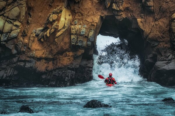 Der Athlet fährt mit dem Boot über die Felsen