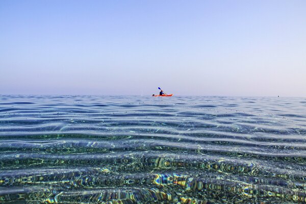 Mann im Kanu schwimmt im Meer