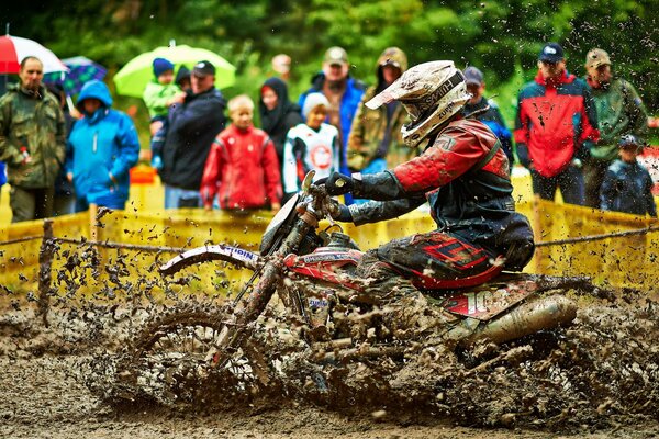 An athlete on a motorcycle rides in the mud