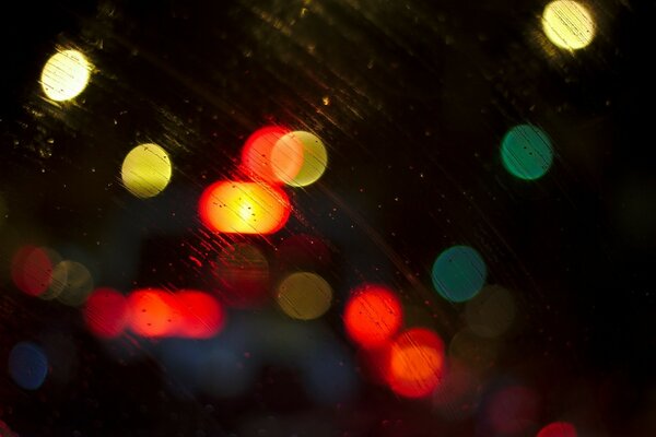 On the street, car headlights shine in the rain