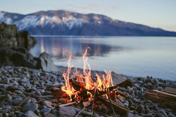 Bonfire on a pebble by a mountain lake