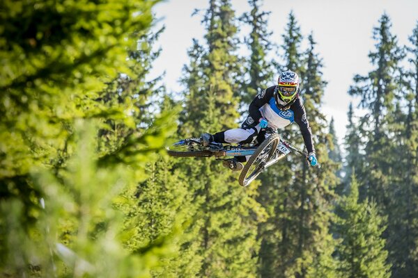 An athlete on a bicycle flies against the background of trees