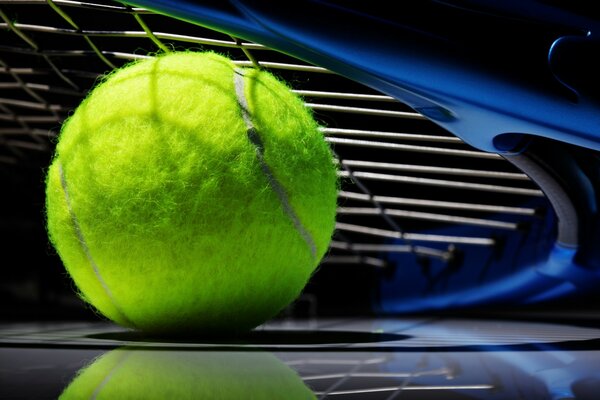 Tennis racket and ball on a black background