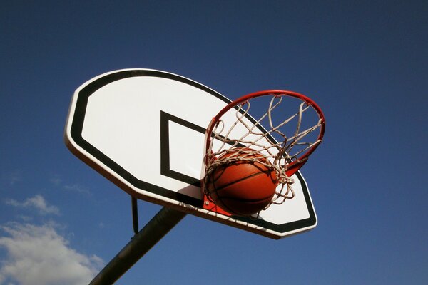 Canestro da basket con la palla sullo sfondo del cielo