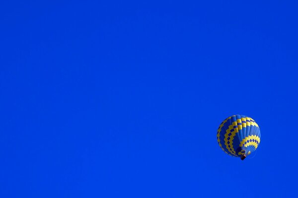 Un palloncino blu e giallo vola lentamente attraverso il cielo