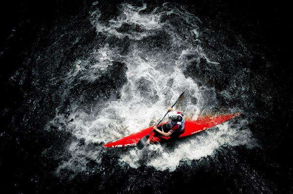 Un hombre remando en un kayak rojo