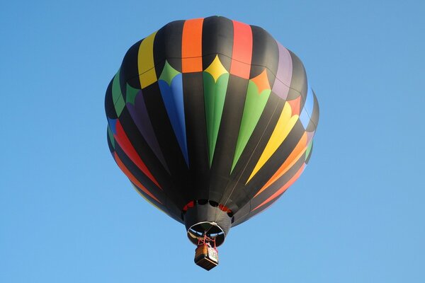 Ein mehrfarbiger Ballon fliegt vor einem blauen Himmelshintergrund