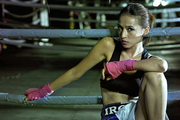 Atleta chica se sienta en guantes de color rosa