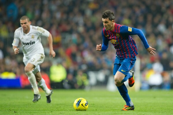 Two football players in motion in front of the ball