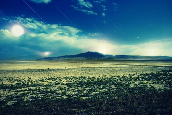 A través de las nubes se ve el sol, y en la distancia sólo las montañas