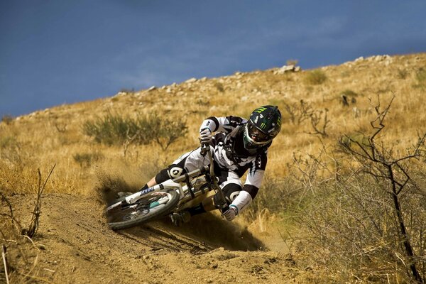 The motorcycle drifts steeply on the sand