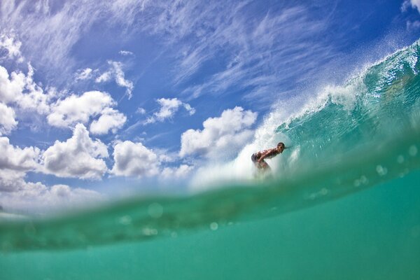 Surfeur dans une vague verte sous un ciel bleu