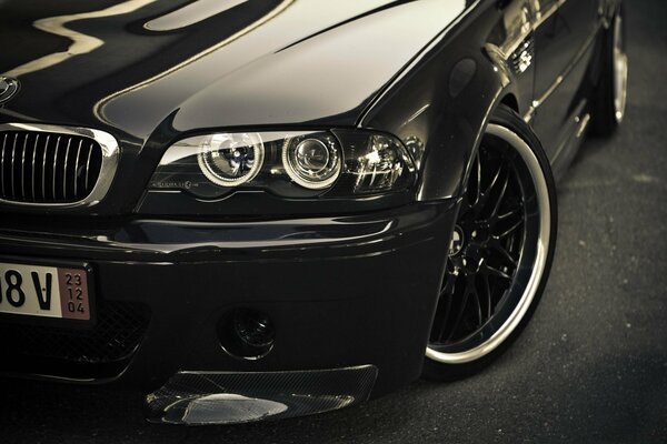 Headlight and front wheel of a shiny black bmw