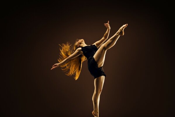 Dziewczyna z rudymi włosami w namiętnie tańcu ciemne tło