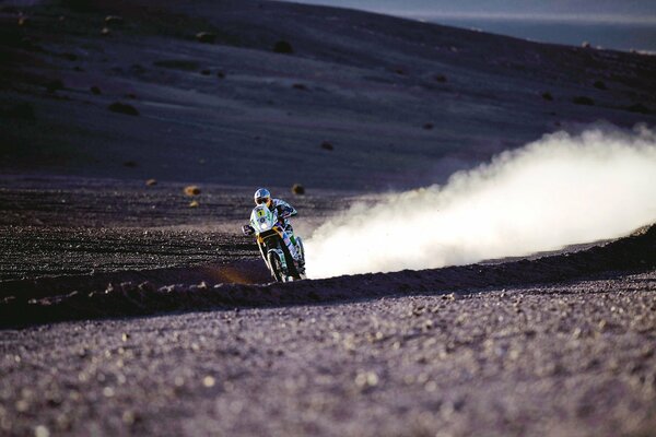 A motorcyclist raises a column of dust