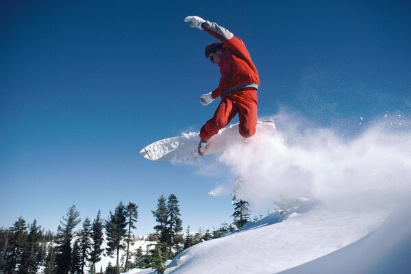 Snowboarder vola dalla montagna sullo sfondo della foresta