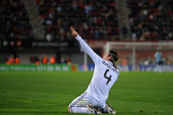 Sergio Ramos est assis sur le terrain de football et montre la main vers le haut