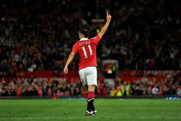 A football player in a red uniform raised his hand with an index finger up