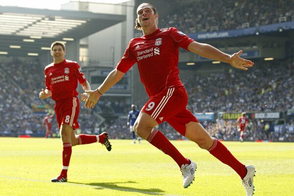 Dos futbolistas del Liverpool corren alegremente por el campo