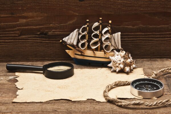 On the table is a magnifying glass with a manuscript, a compass and a rope