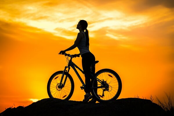 Mädchen auf einem Fahrrad auf Sonnenuntergang Hintergrund