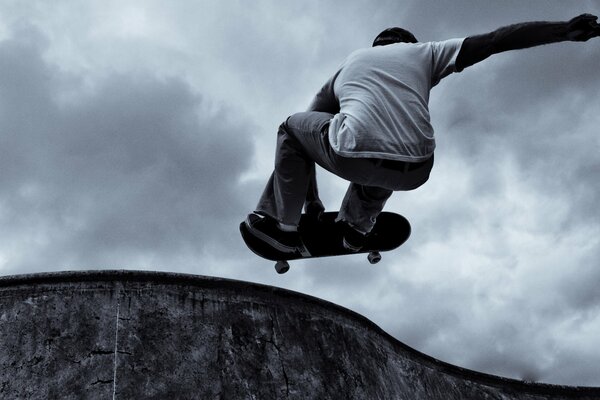 Skateur effectue un tour sur fond de nuages gris