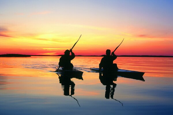 Deux personnes en kayak nagent sur la surface de l eau au coucher du soleil