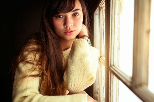 A young girl is bored at the window