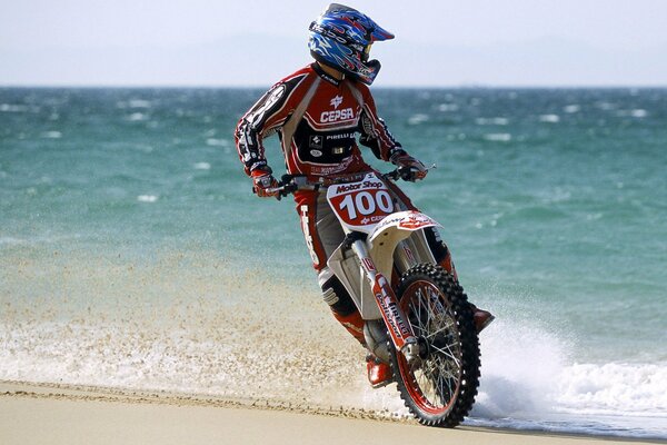 Motard sur une moto sur une côte de sable