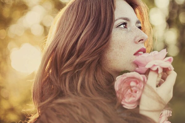 Fille avec des taches de rousseur d été avec des fleurs à la main